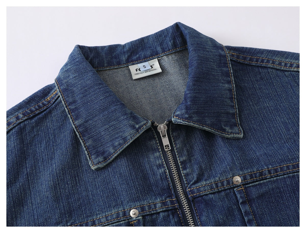 Close-up of a dark blue denim jacket collar, front zipper, and upper chest pocket stitching.