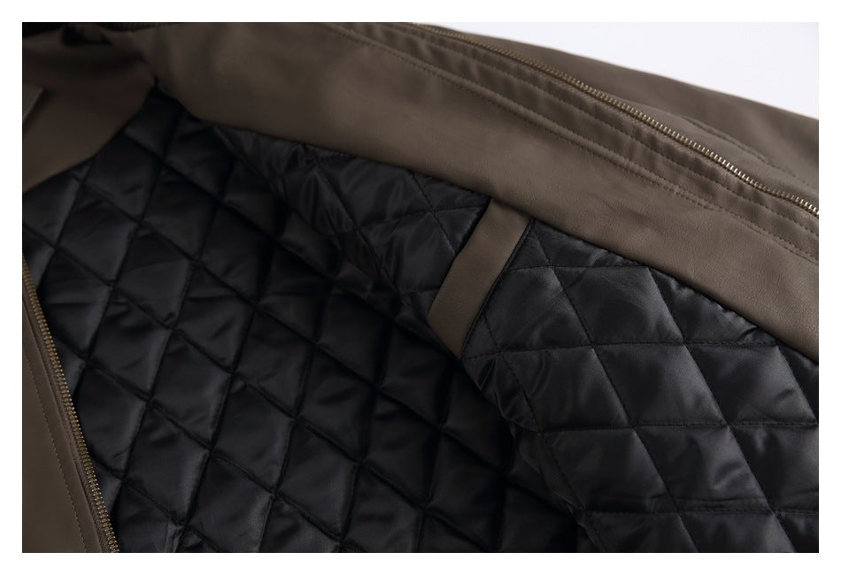 Close-up of a brown jacket’s open edge, gold-tone zipper, and black diamond-quilted lining.