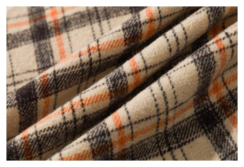 Close-up of beige plaid fabric folded into soft ridges, with orange and dark lines.