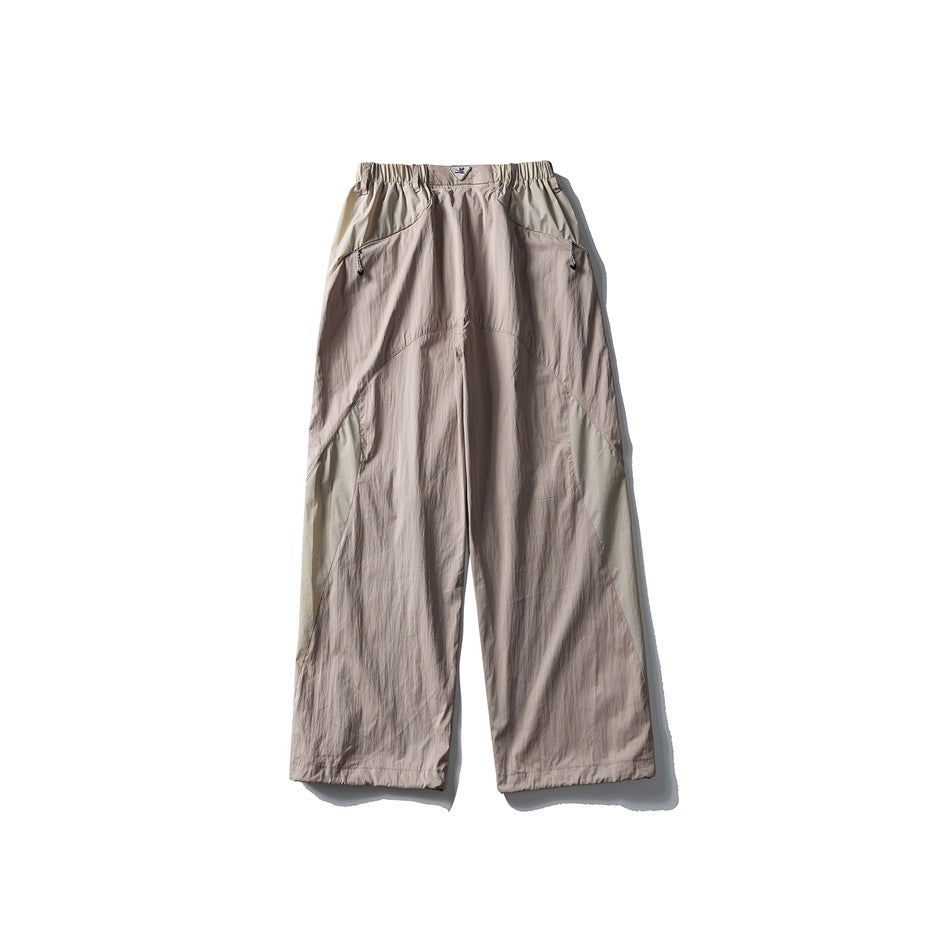 Pinkish beige wide-leg pants with light olive contrast panels, elastic waist and zip pockets, flat lay back view