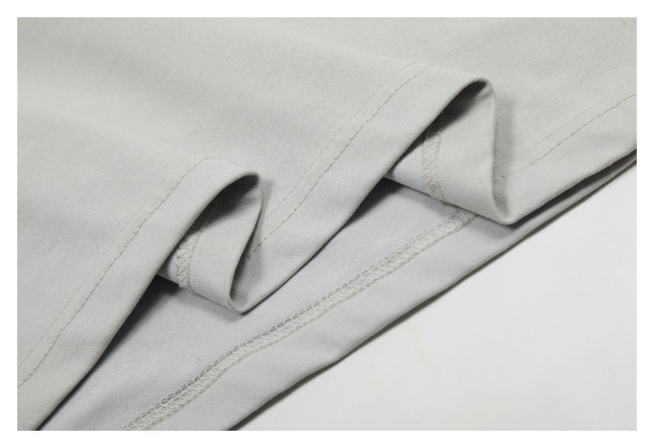 Close-up of folded light gray shirt fabric showing the hem and overlocked interior seam.