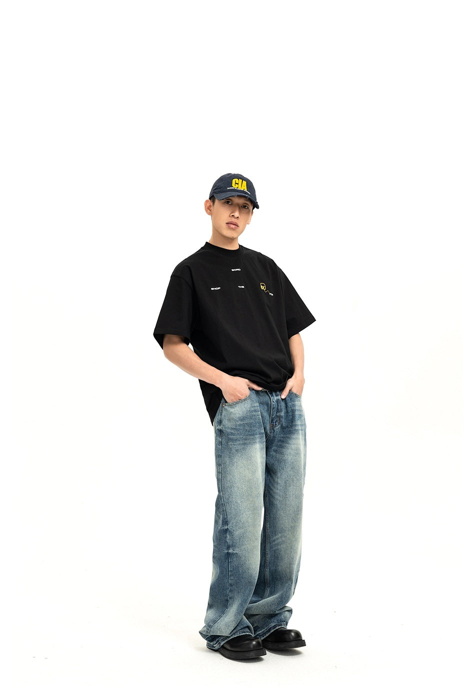 Model wearing a black oversized graphic T-shirt and loose blue jeans, shown from the front.