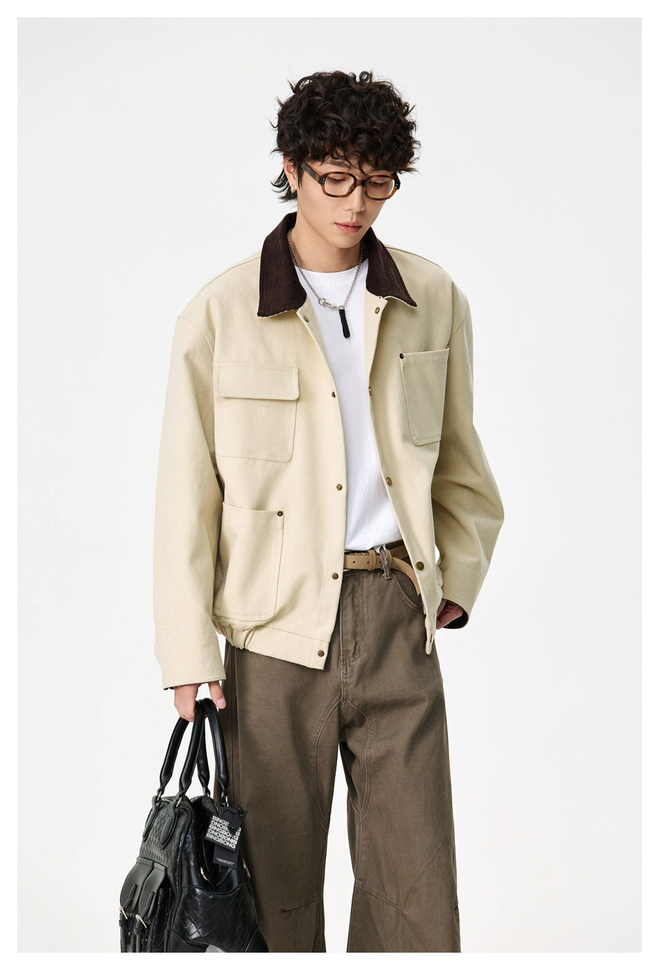 Model wearing an open cream jacket with a dark brown collar and four pockets, over a white shirt.