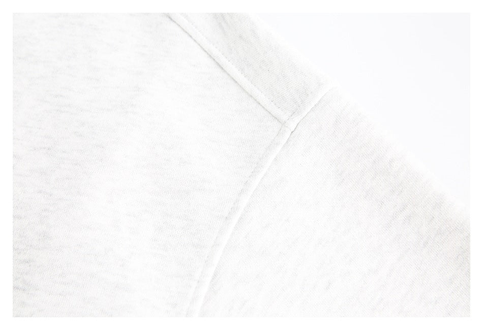 Close-up of a seam joining panels on a light heather gray garment.