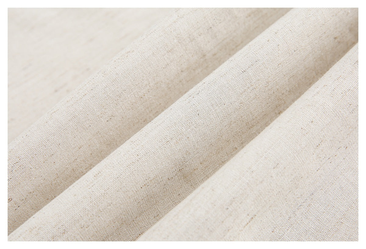 Close-up of light beige, subtly speckled fabric arranged in soft folds.