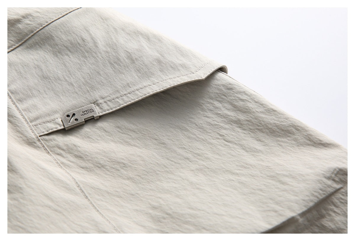 Close-up of light beige pants with a flap pocket and a small metal tag marked “SPECIAL VARIATION.”