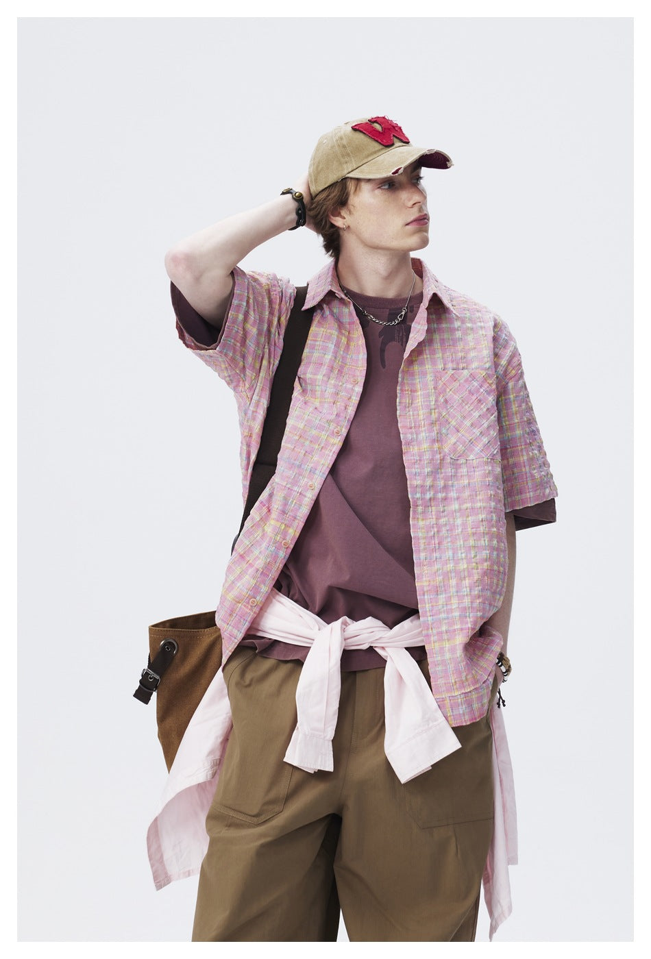 Model wearing a pink multicolor plaid short-sleeve button-up shirt over a mauve top.