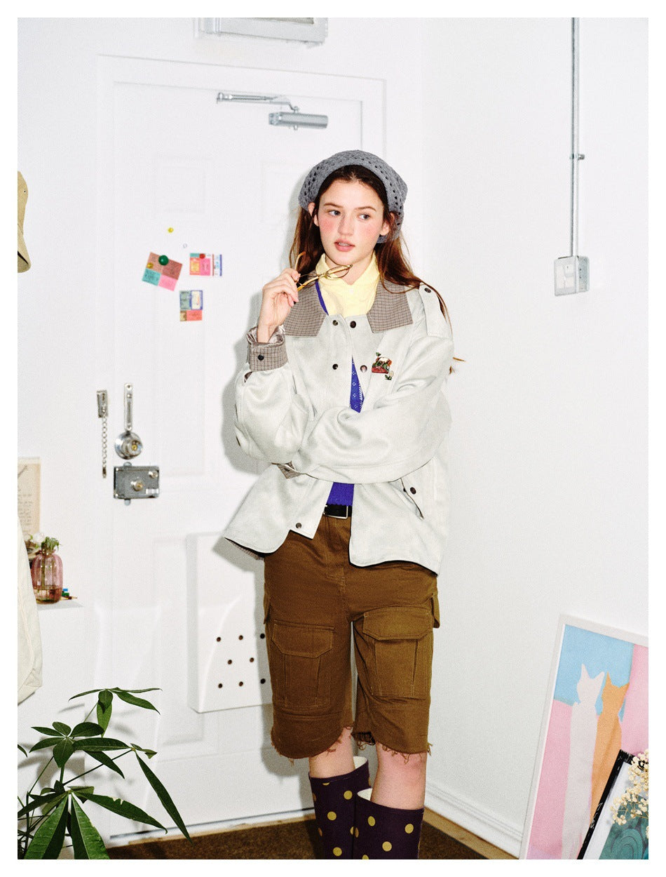 Model wearing the light gray plaid-collar jacket open over a purple knit and yellow collar with brown cargo shorts