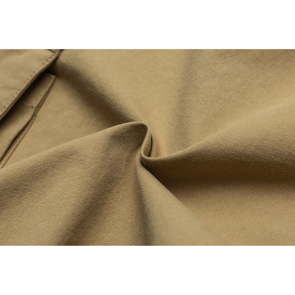 Close-up of tan fabric gathered into folds, showing its surface texture.
