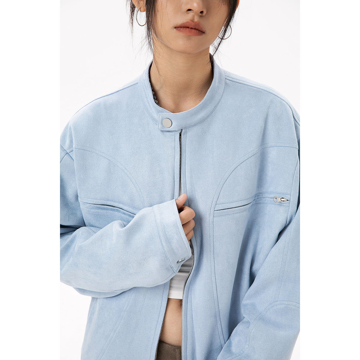 Close-up of a light blue jacket showing its stand collar, snap tab, center zipper, and zippered chest pockets.
