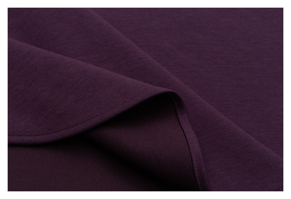 Close-up of the plum shirt's folded hem, showing its stitching and fabric on both sides.