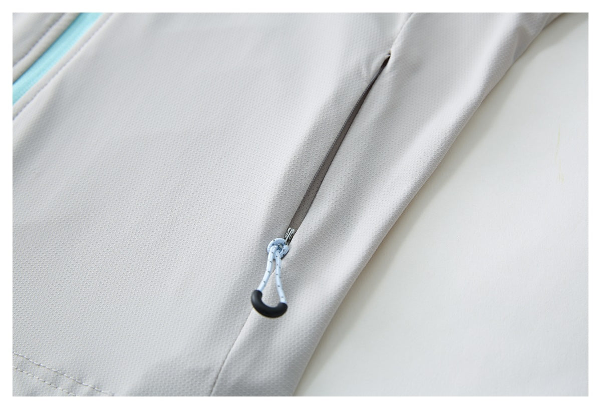 Close-up of a concealed gray zipper pocket with a pale blue cord pull on a light gray garment.
