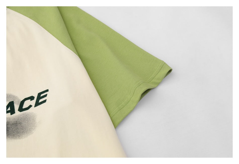 Close-up of a green short sleeve and its stitched hem against the cream shirt body.