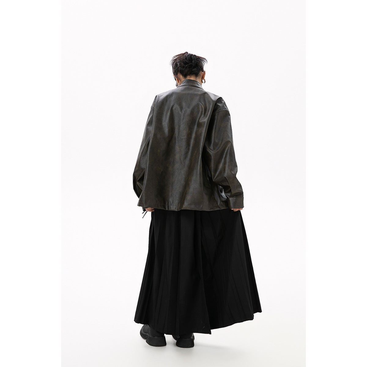 Back view of a model wearing a dark oversized jacket and a long, flowing black skirt.