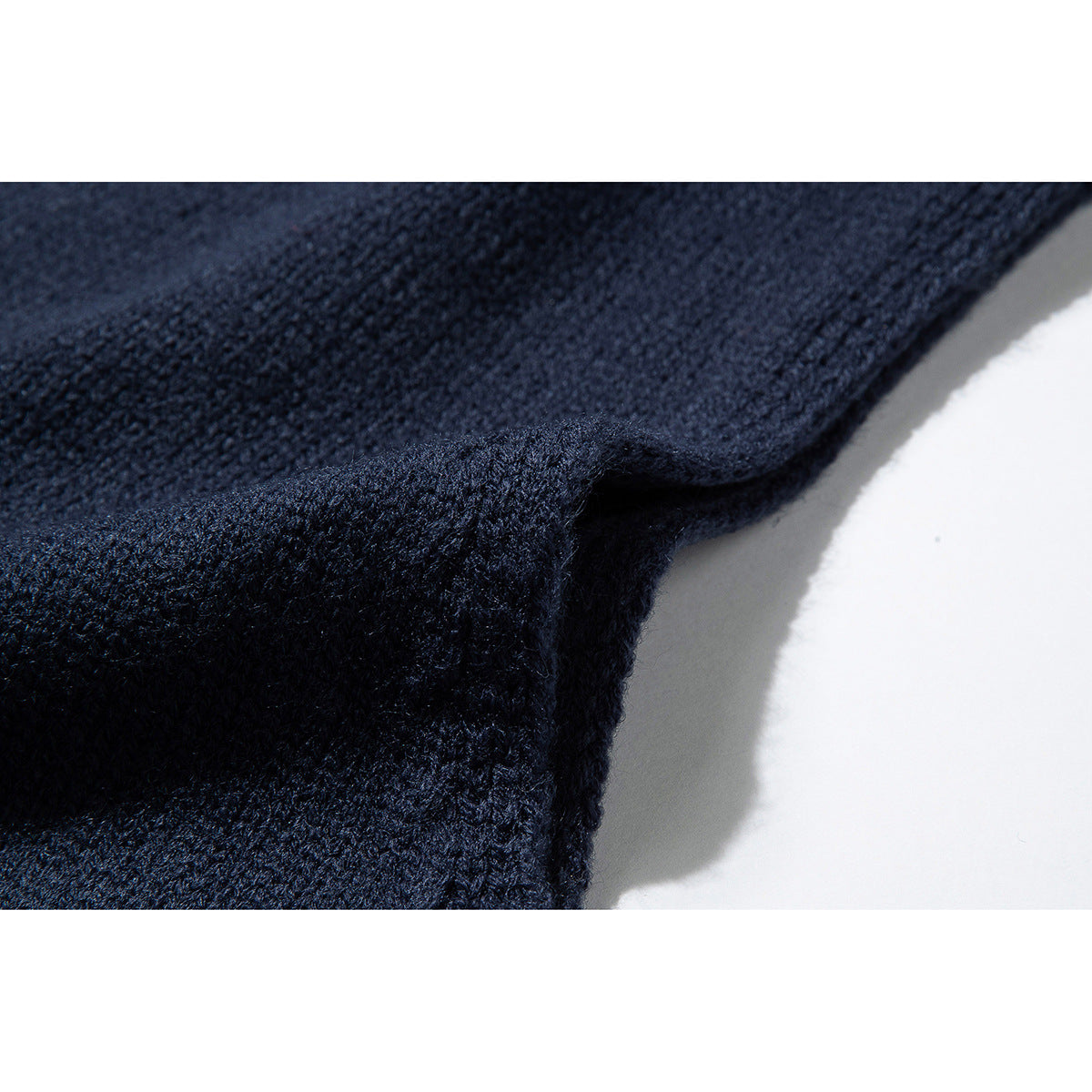 Close-up of the dark navy knit fabric and folded edge of a sweater vest.