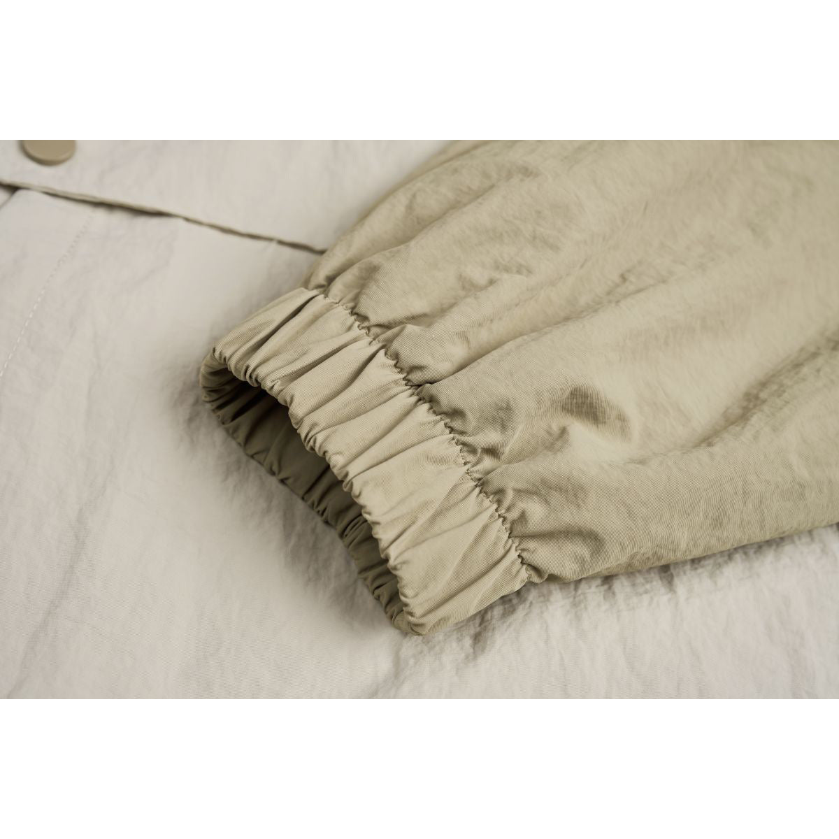 Close-up of the jacket's gathered elastic cuff in beige fabric.