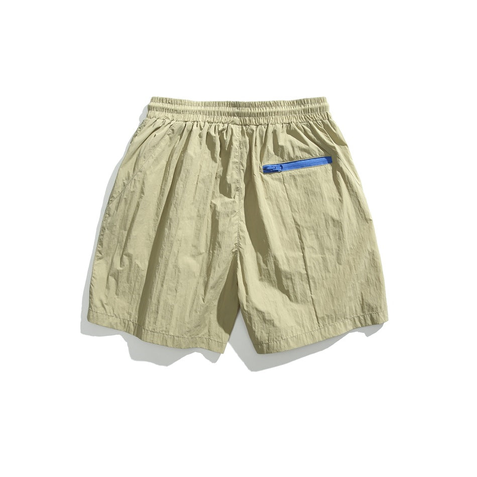 Back view of pale khaki shorts with an elastic waistband and blue zip pocket.