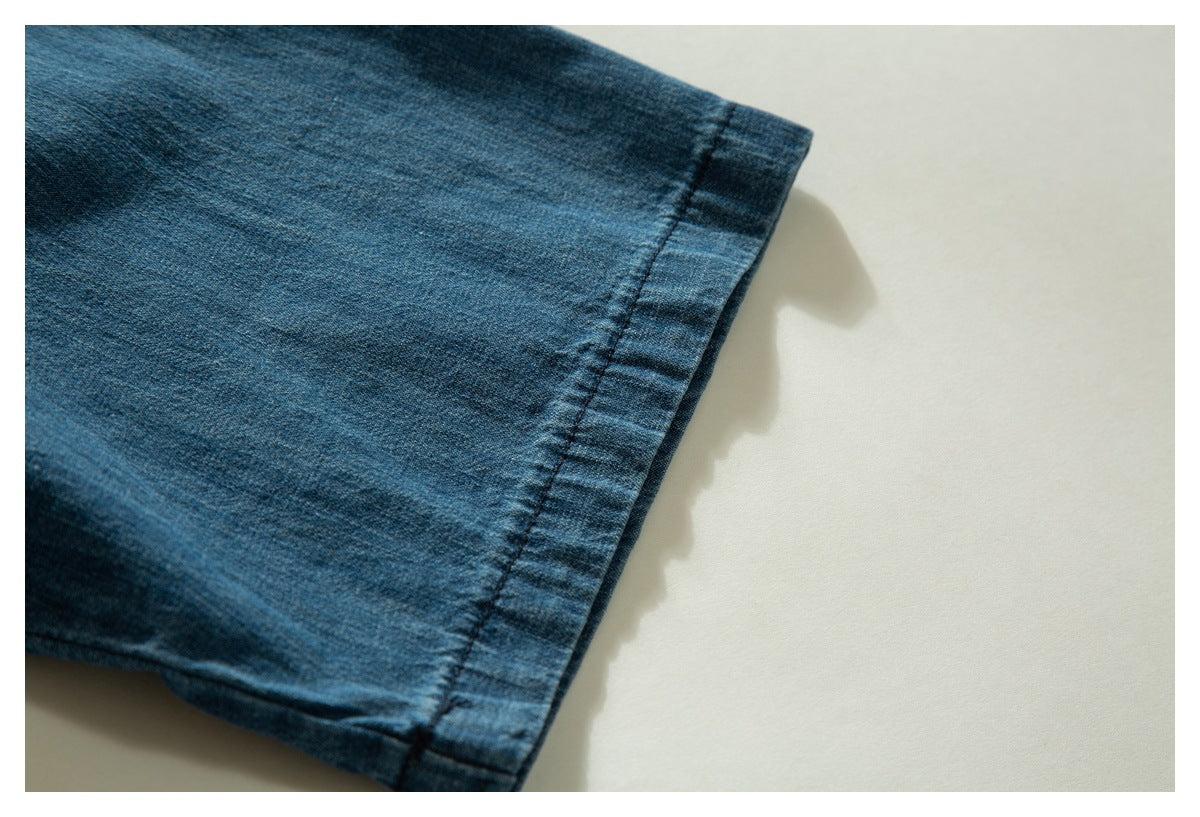 Close-up of a blue denim garment's stitched sleeve cuff against a light background.