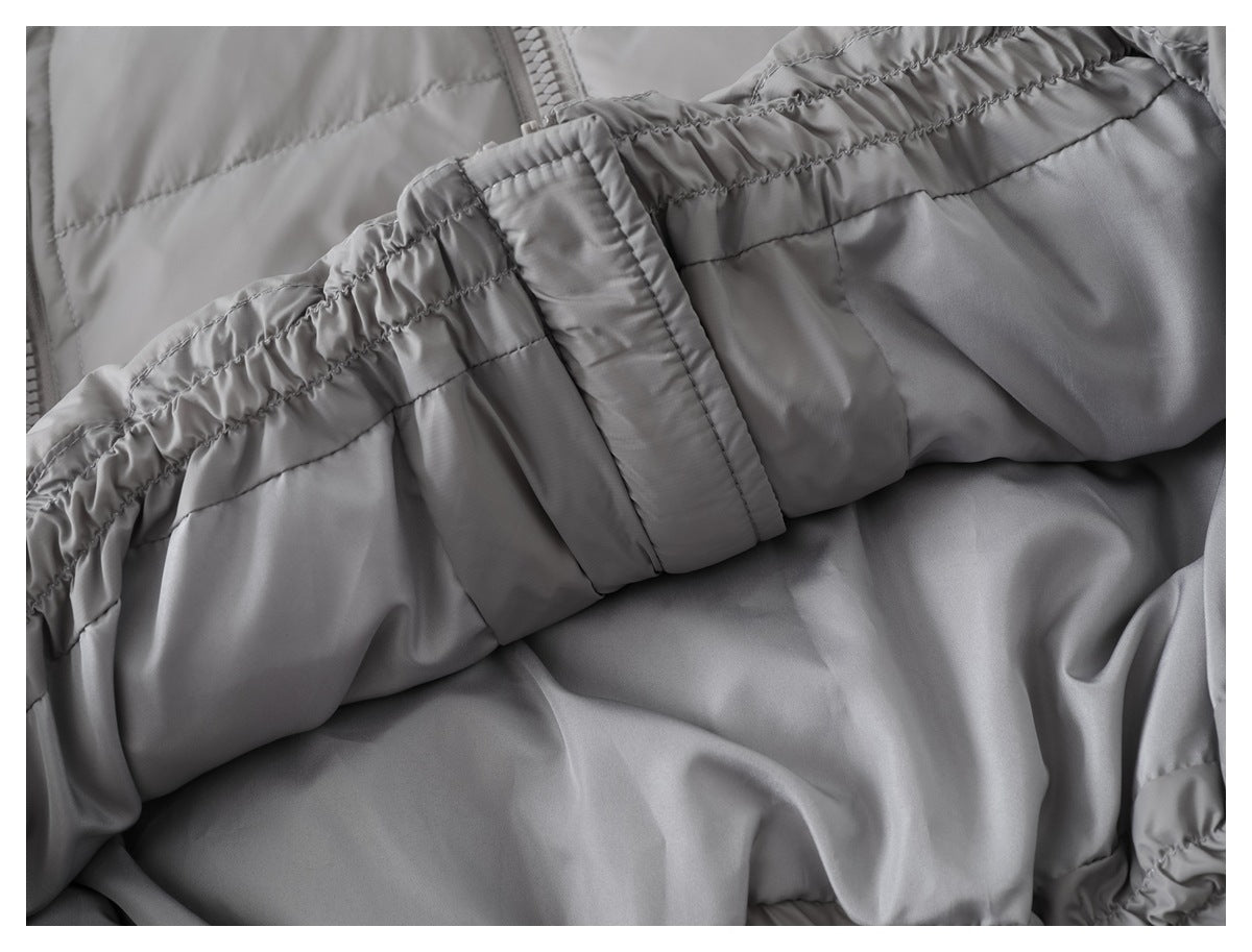 Close-up of a gathered elastic edge and stitched fabric panel on a gray padded garment.