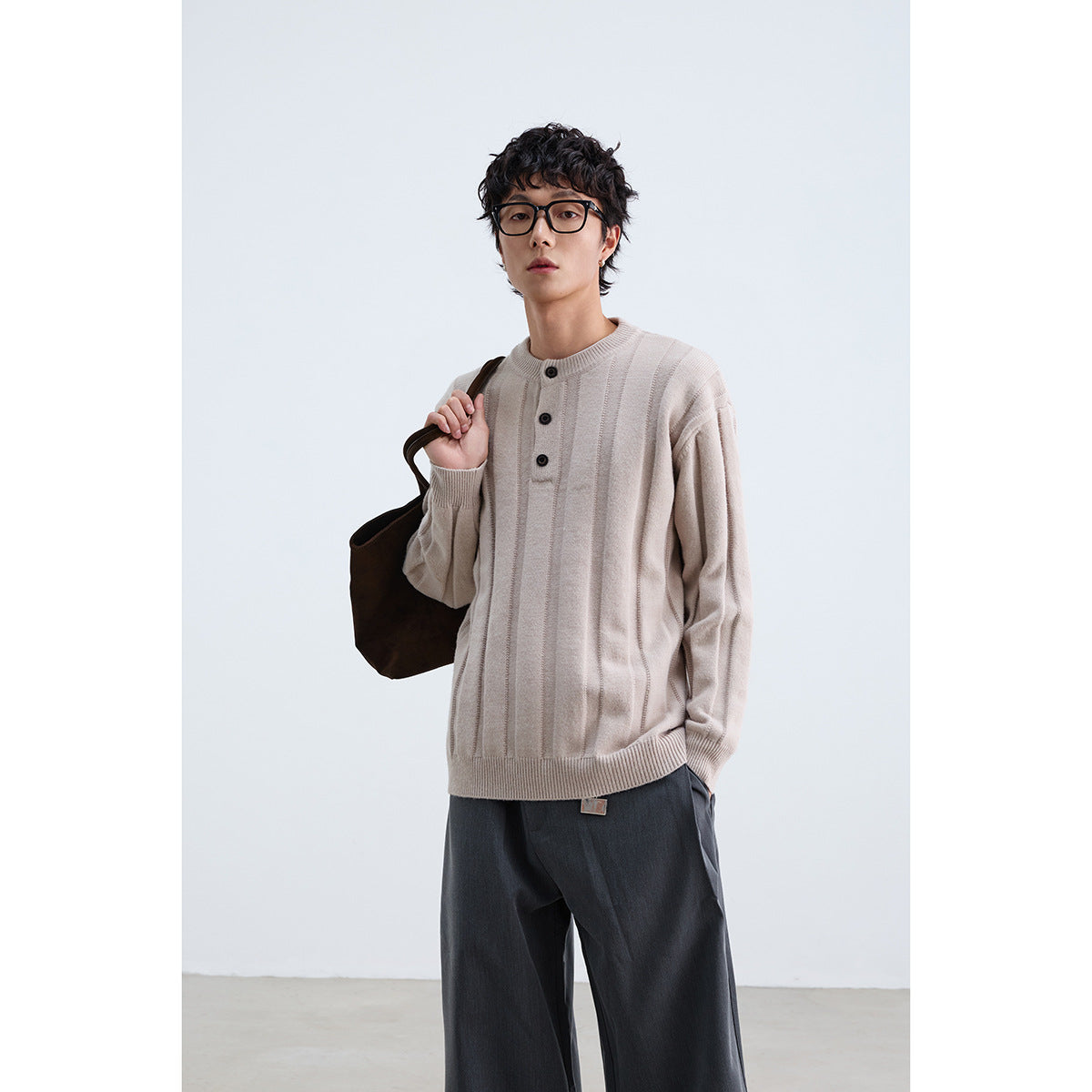 Model wearing a light beige ribbed sweater with a round neck and three-button placket.