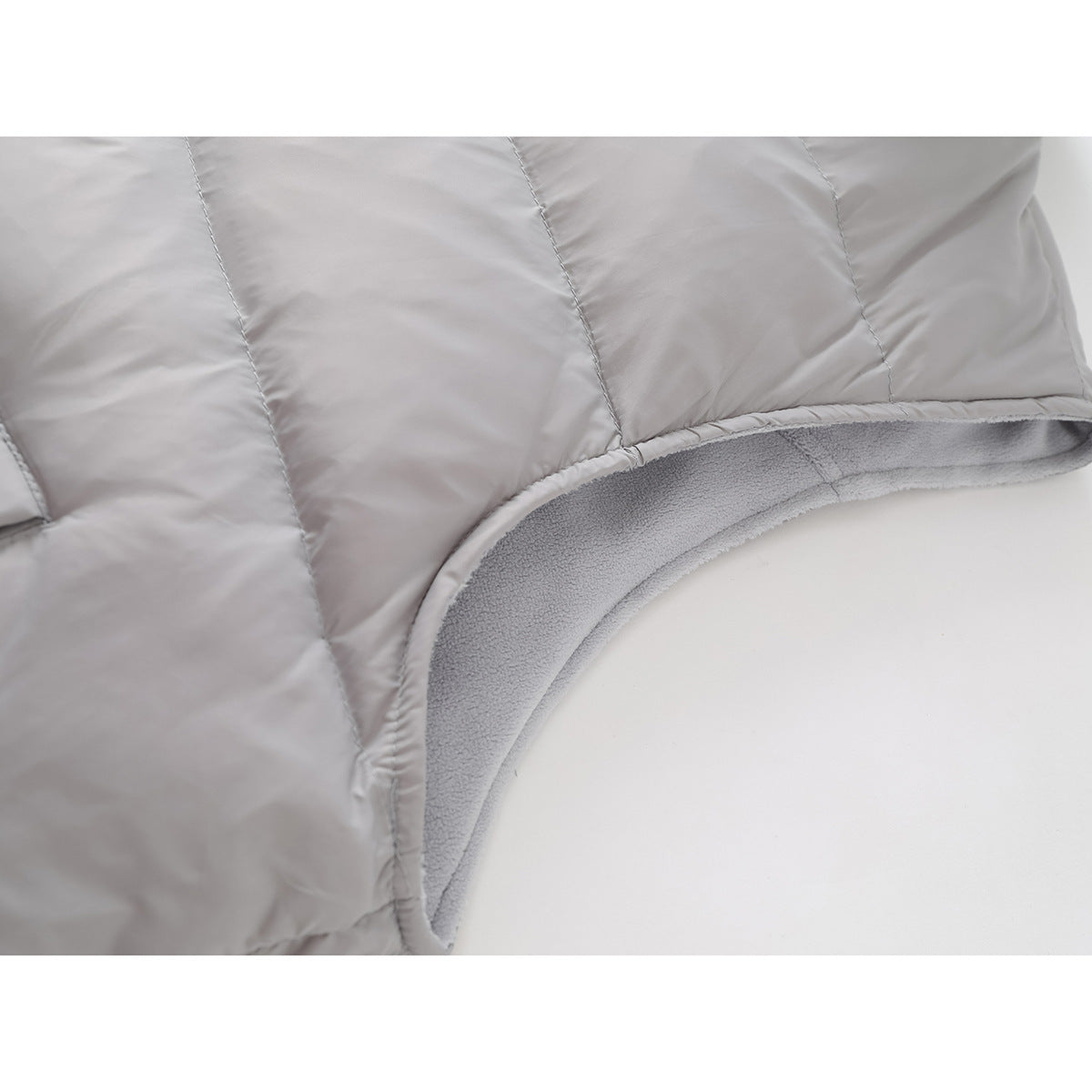 Close-up of the light gray quilted vest edge, showing its soft fleece lining and curved opening.