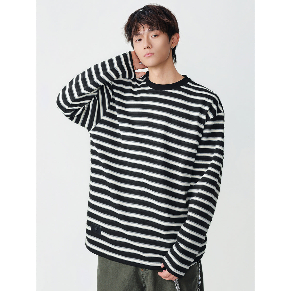 Model wearing an oversized black shirt with white horizontal stripes, long sleeves, and a black crew neck.