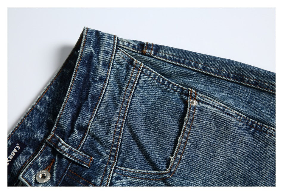 Close-up of the front waistband and pocket area of faded blue jeans with a metal rivet and belt loop.