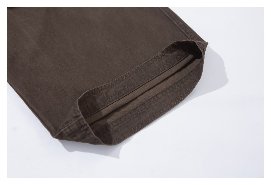 Close-up of the folded hem and stitching on dark brown trousers.