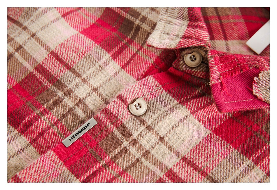Close-up of the red and beige plaid shirt fabric, buttons and small metal chest tag.
