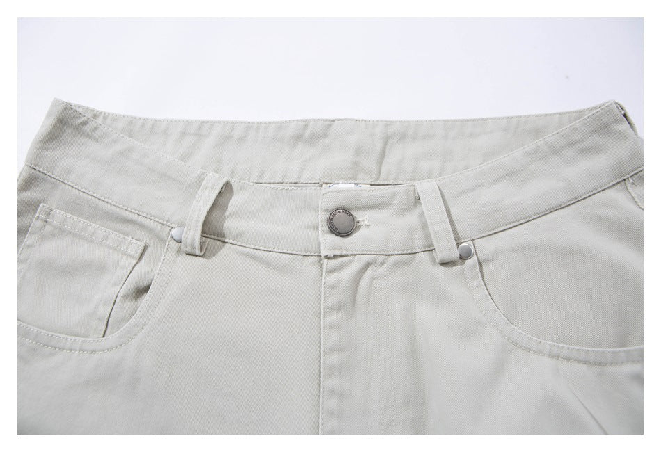 Close-up of light gray shorts showing the waistband, button, belt loops, fly seam, and front pockets.