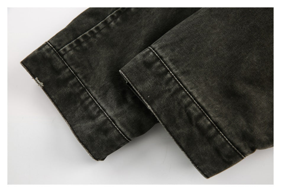 Close-up of two folded edges of a dark charcoal garment, showing stitched hems.