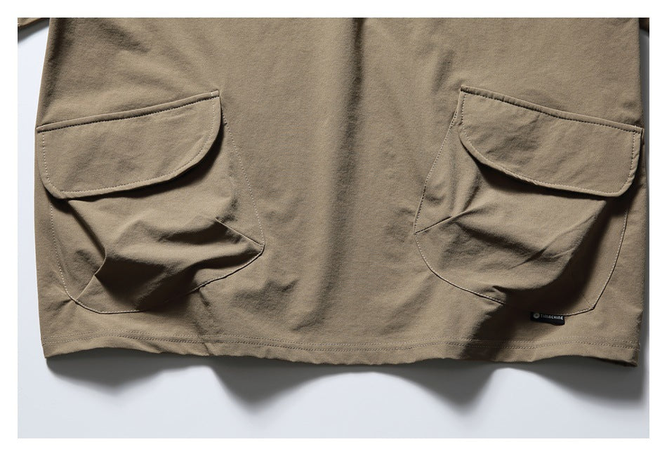 Lower front of the taupe top showing two large flap pockets and the hem.