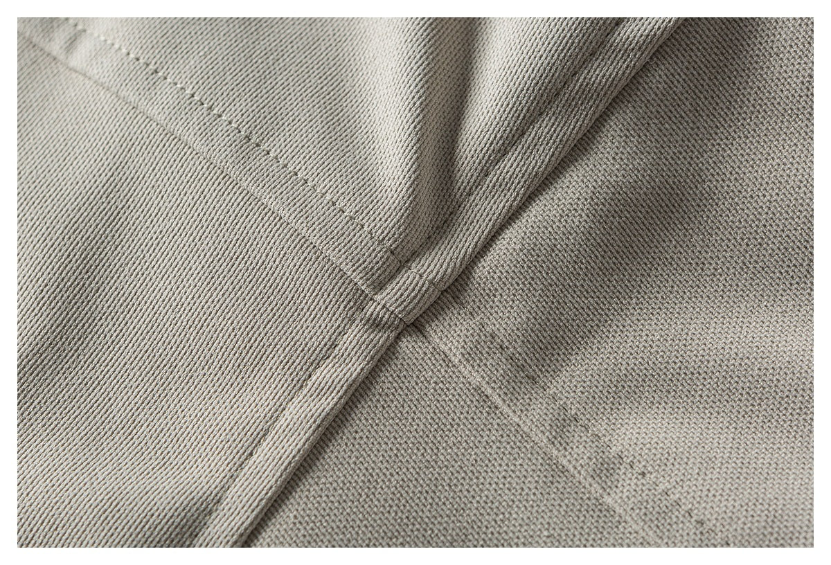 Close-up of light taupe-gray fabric showing a diagonal seam, folded edge, and fine textured weave.