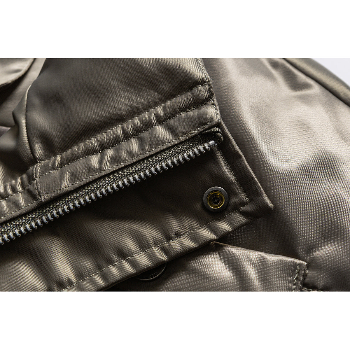 Close-up of a glossy taupe jacket's zipper, flap, and snap fastener.