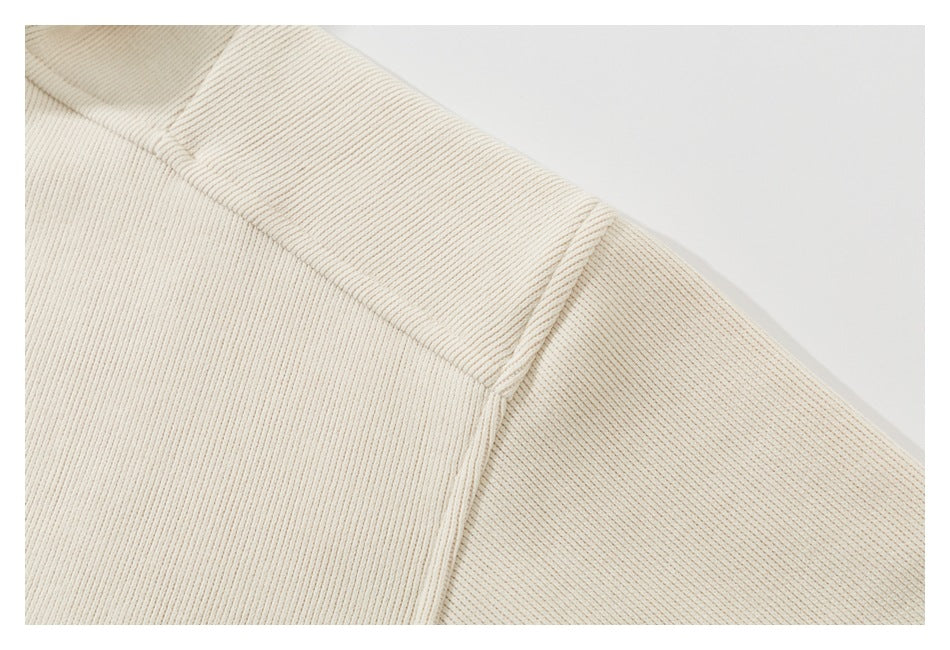 Close-up of the ivory ribbed top's shoulder seam and sleeve stitching.