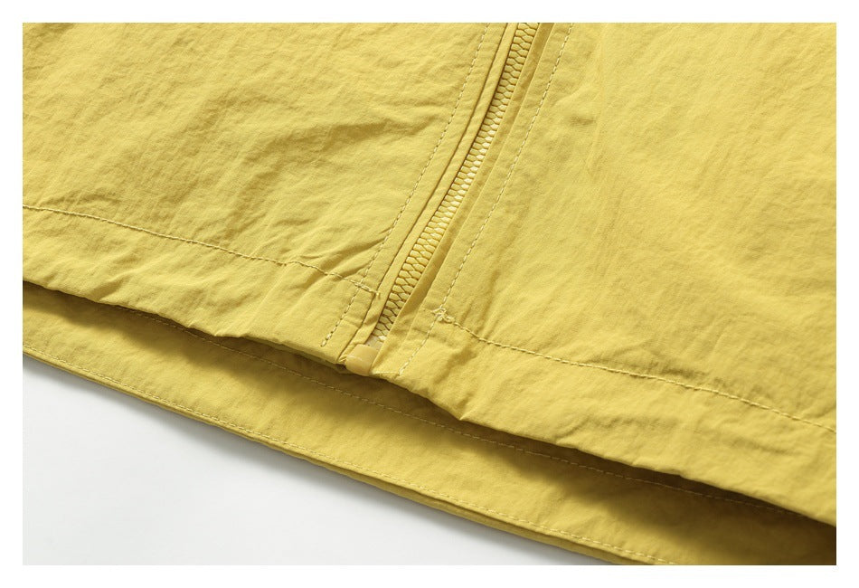 Close-up of a mustard-yellow jacket showing its zipper, stitched panels, and lower hem.