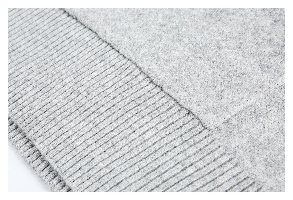 Close-up of light gray knit fabric meeting a wide ribbed edge.