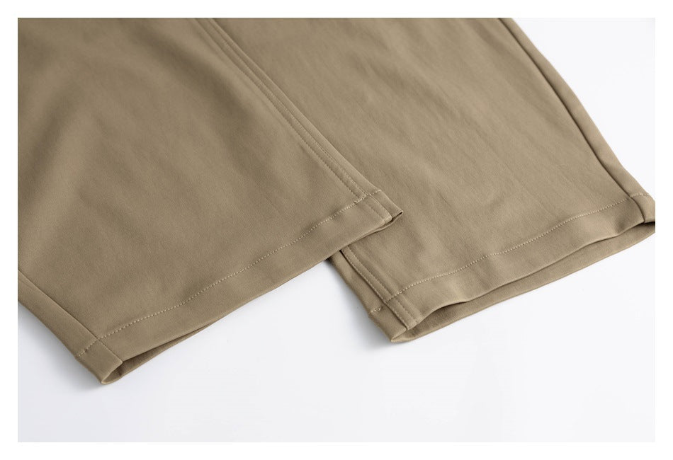 Close-up of the tan trouser legs and stitched hems laid flat on a white background.