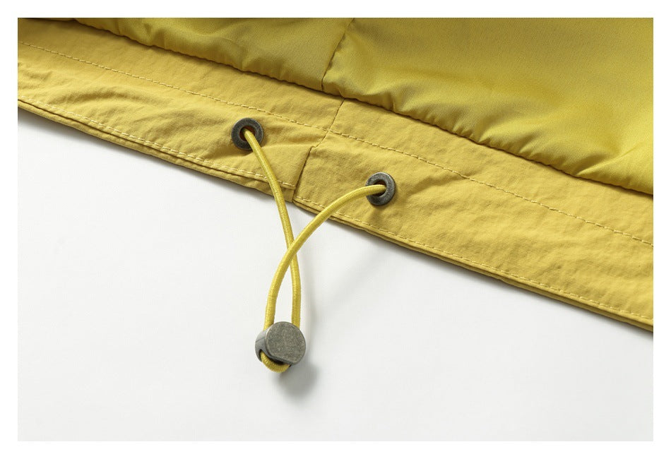 Close-up of a mustard-yellow garment hem with metal eyelets and an adjustable drawcord toggle.