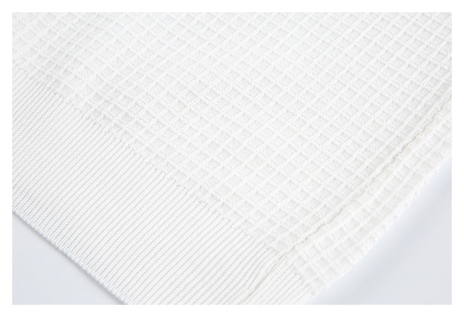 Close-up of white textured fabric with a raised geometric weave and ribbed edge.