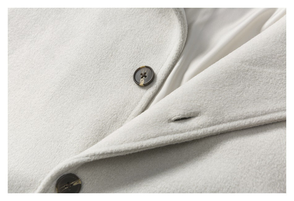 Close-up of dark buttons and a buttonhole on the off-white coat.