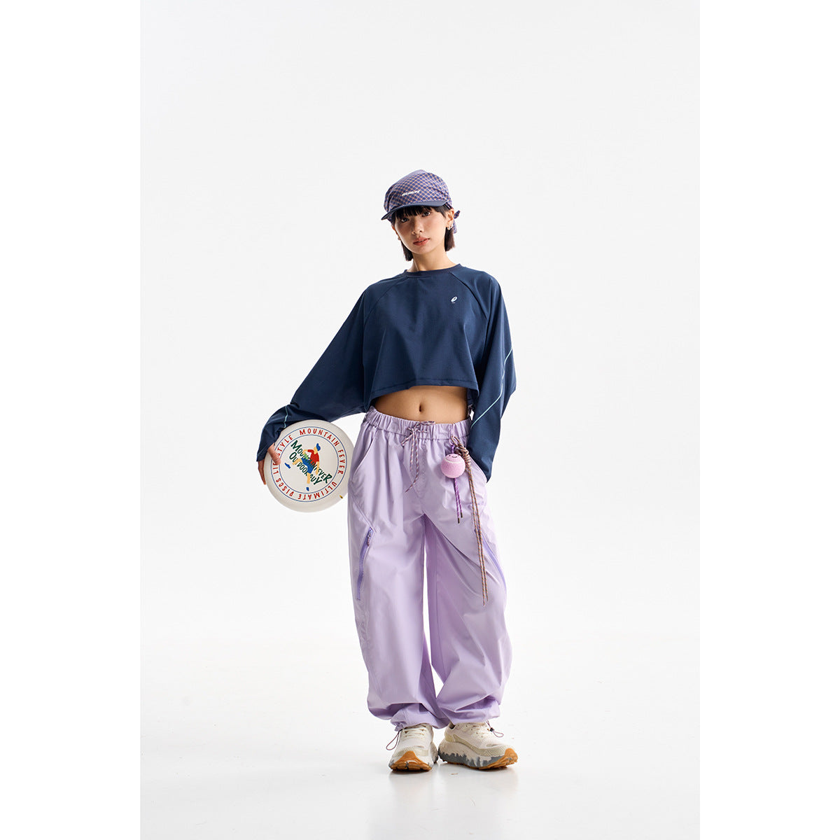 Model wearing a navy cropped long-sleeve top with lavender drawstring pants in a studio.
