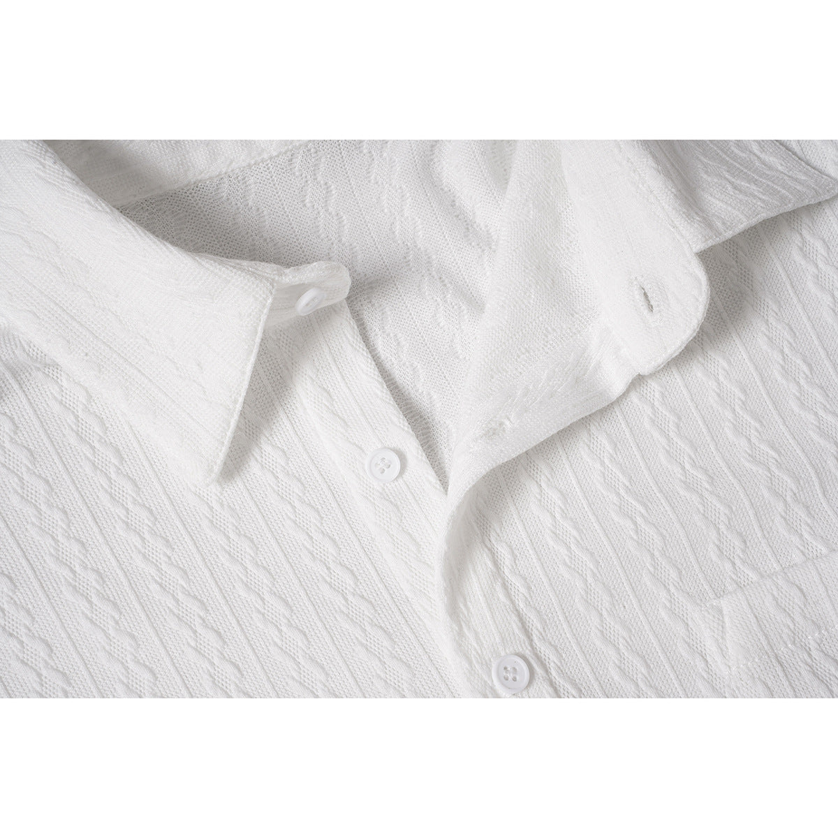Close-up of a white shirt's pointed collar, button placket, buttons, and textured knit pattern.