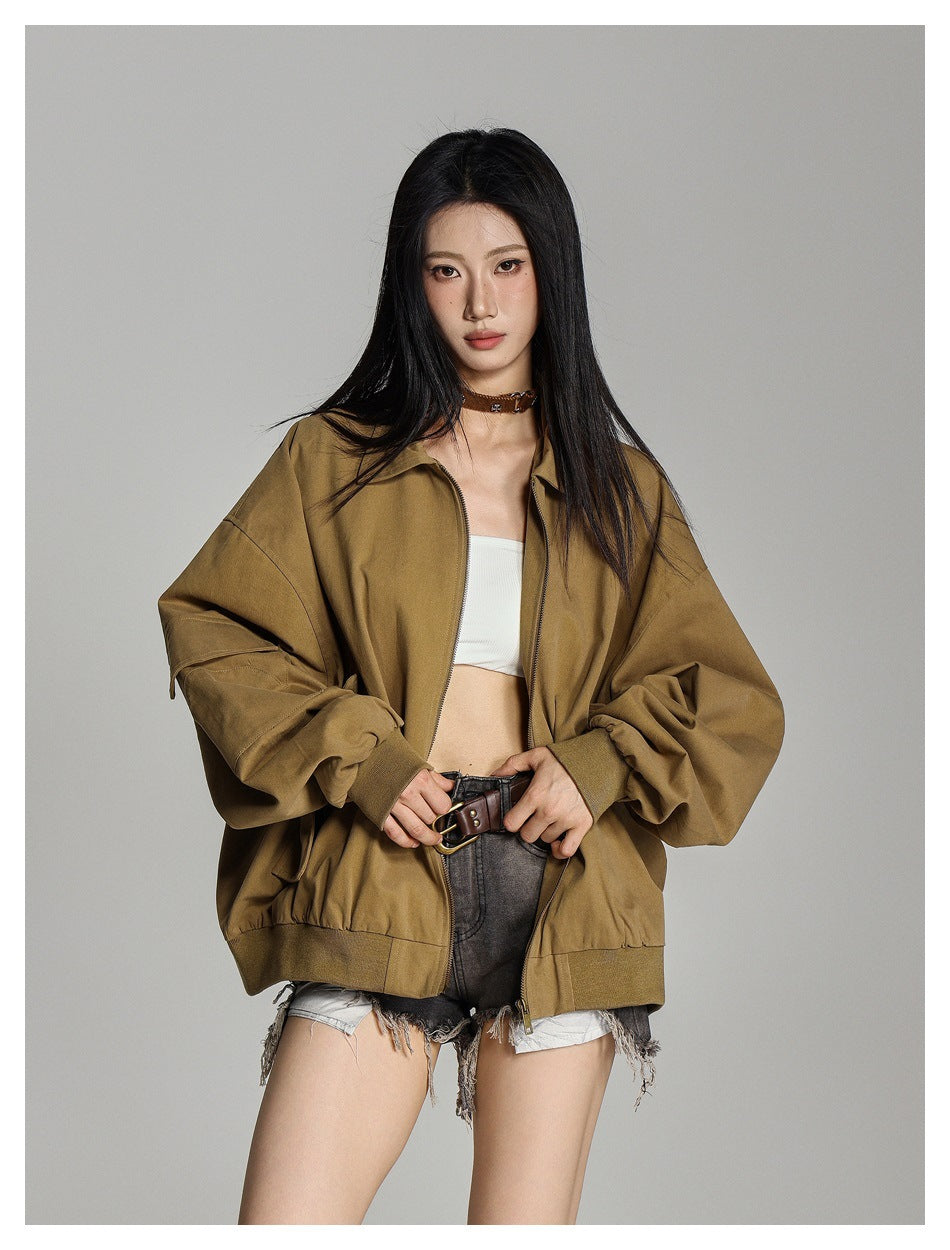 Model in an open tan-brown oversized jacket with voluminous sleeves, ribbed cuffs, and a front zipper.