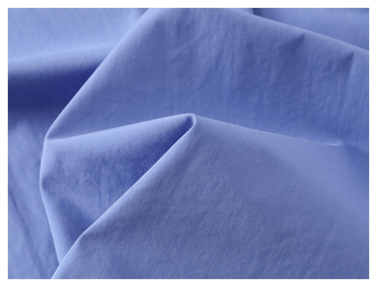 Close-up of light blue shirt fabric arranged in soft folds.