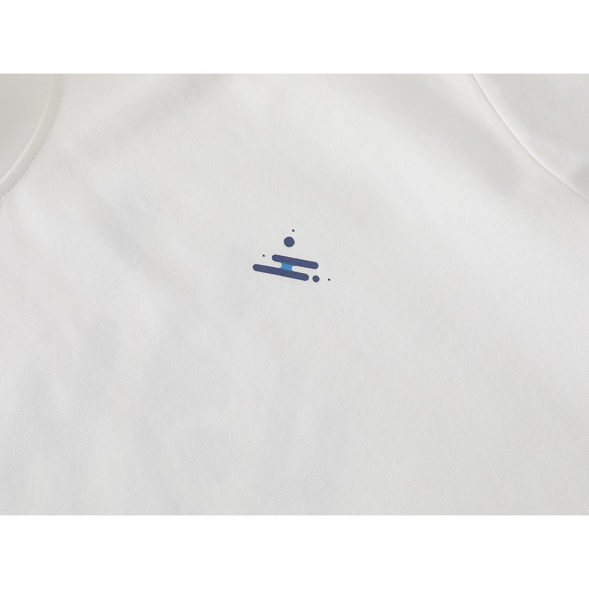 Close-up of a small navy-and-blue abstract emblem printed on the chest of a white T-shirt.