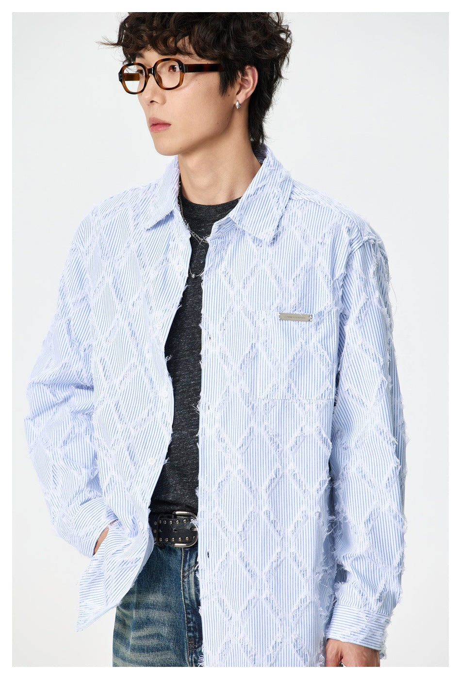 Close front view of a model wearing a light blue pinstriped shirt with frayed diamond patterns and a chest pocket.