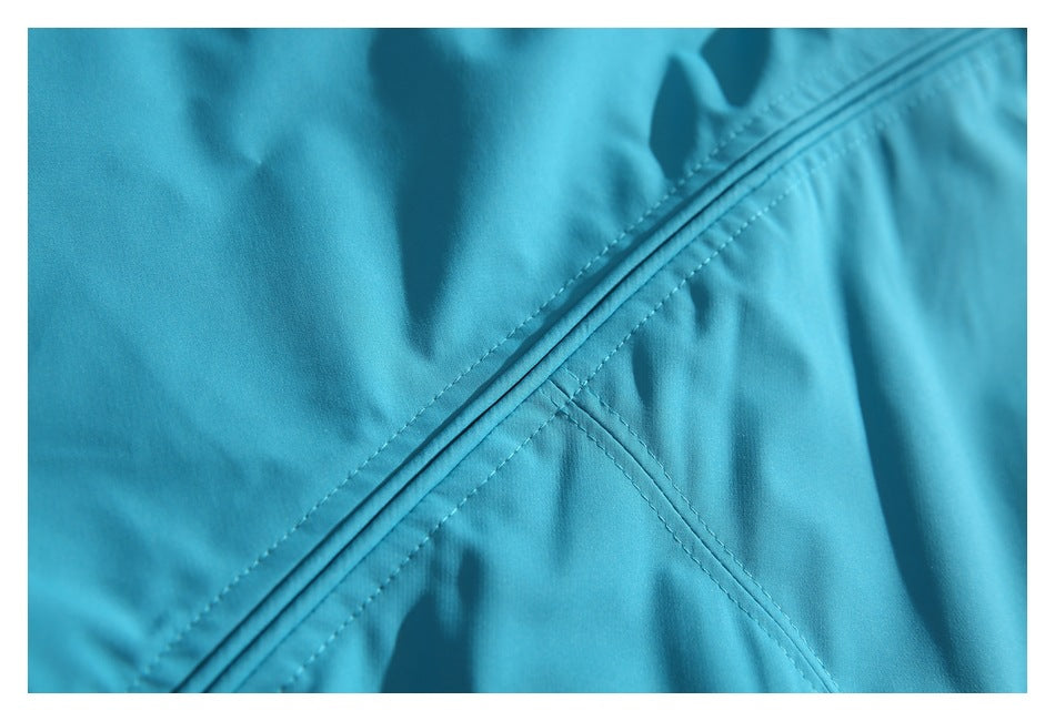 Close-up of turquoise jacket fabric with a diagonal stitched seam.