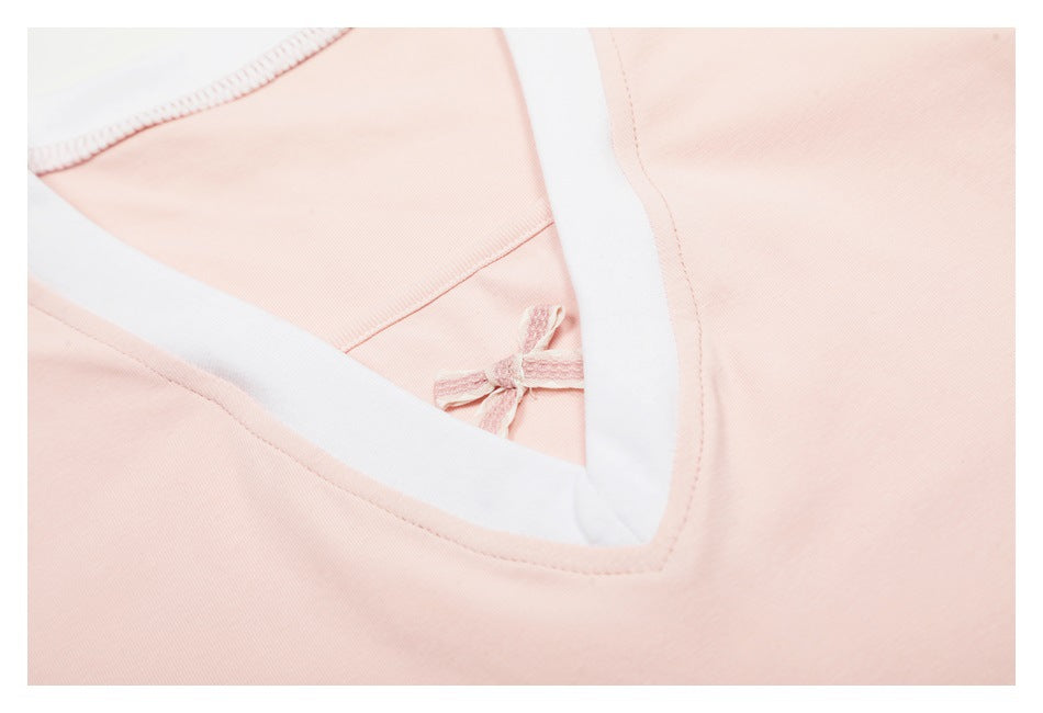Close-up of the pale pink V-neck top showing white neckline trim and a small decorative bow.