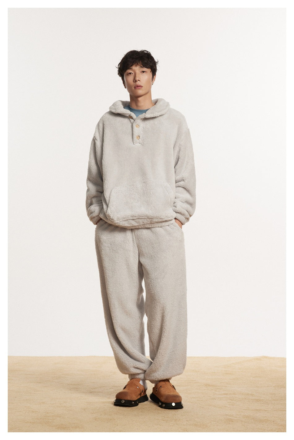 Model wearing a gray plush pullover with matching gray pants and brown clogs against a plain backdrop